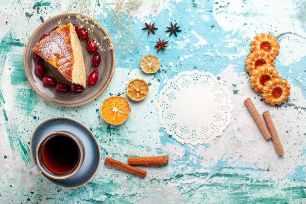 茶顶视图蛋糕片上有饼干和一杯茶 蓝色的表面上有水果蛋糕烤馅饼饼干甜派烘焙食品烘焙