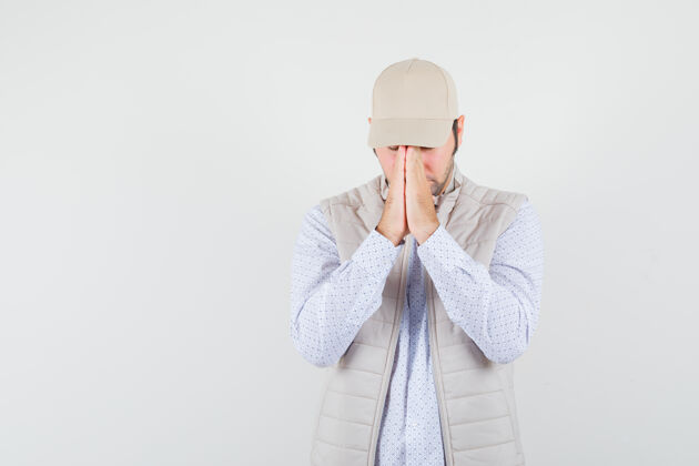 男人年轻人穿着米色夹克 戴着帽子 站在祈祷的姿势 专注地看着前方成年人人帽子