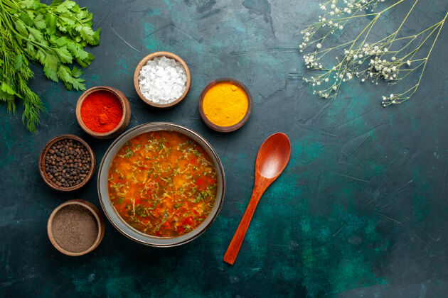 视图俯瞰美味的蔬菜汤与不同调味料的深绿色表面食物餐蔬菜汤配料产品不同勺子勺子