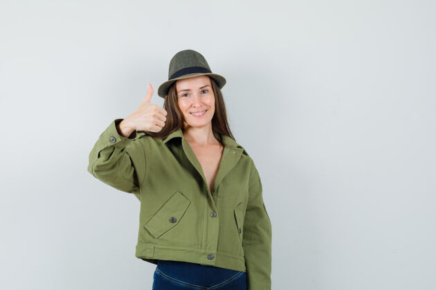 帽子穿着夹克 裤子 帽子的年轻女士竖起大拇指 看上去很高兴裤子时尚夹克