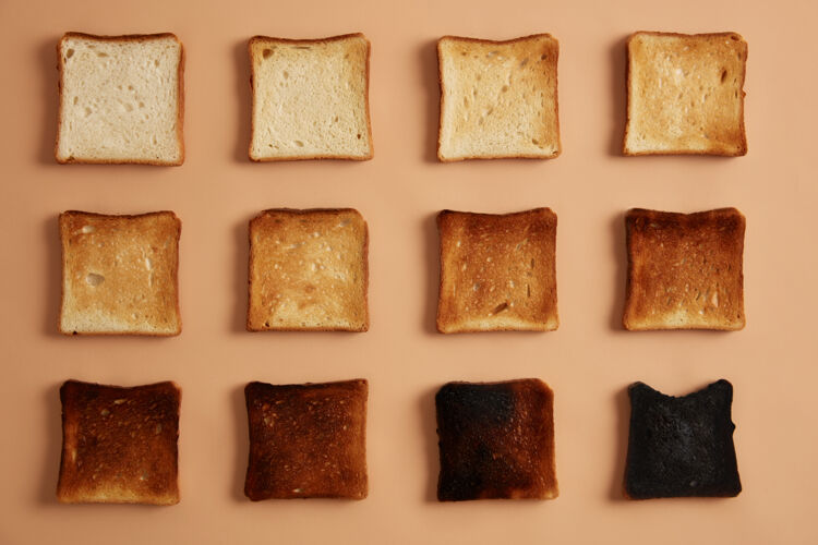 碳水化合物面包片不同程度的烤面包排成一排在米色背景下吐司或零食吃阶段的烤面包健康饮食 零食和节食的概念摄影棚照片传统块饮食