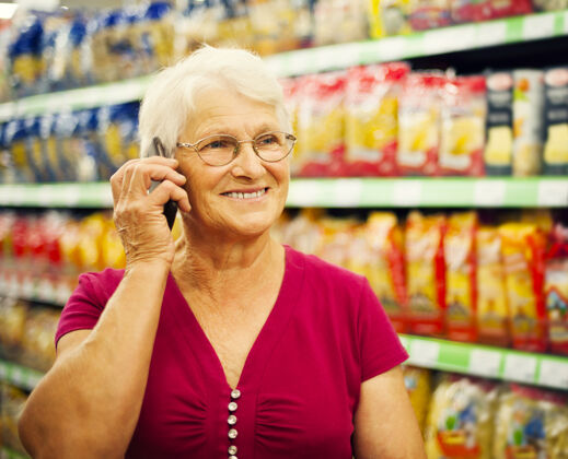 欢呼超级市场的老太太在打电话市场顾客买