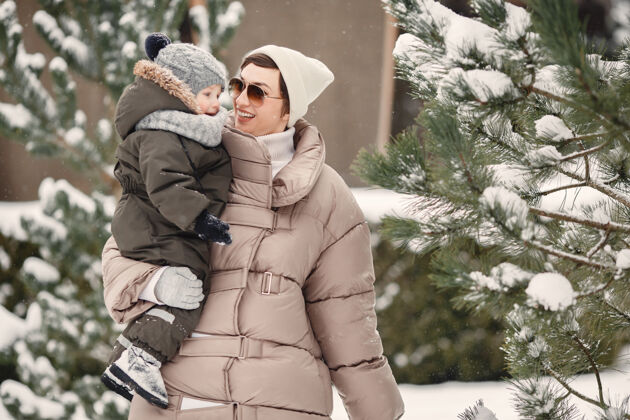 家庭一家人穿着冬装在雪林里度假公园雪松树