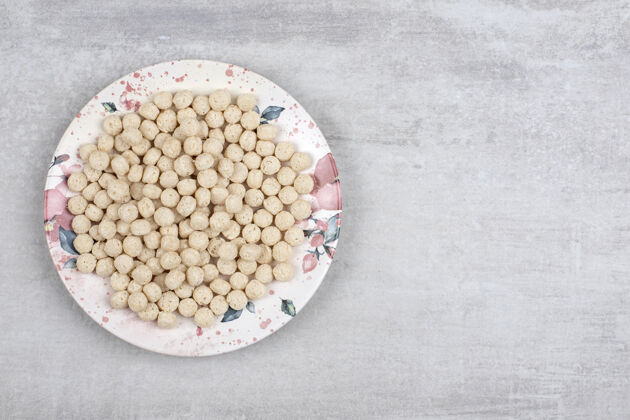 谷类食品石头桌上摆满了玉米粒球的白色盘子干玉米自然