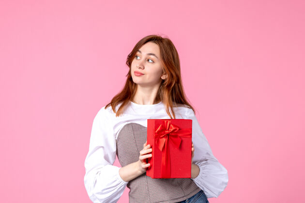 包装前视年轻女性以粉色背景上的红色礼包送礼恋爱日期三月横向送礼香水女士照片金钱平等礼品年轻女性香水