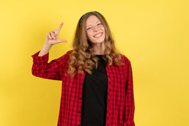 人类正面图穿着红色格子衬衫的年轻女性站在黄色背景上微笑着模特女孩女人色彩情感人类人年轻女性漂亮