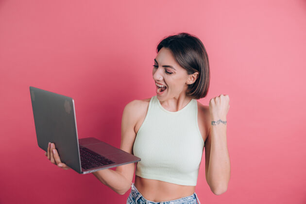胜利粉色背景的女人拿着笔记本电脑工作成人个人电脑