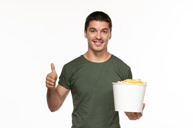 电影正面图身着绿色t恤的年轻男子拿着篮子和土豆在白色背景上孤独地享受电影电影院微笑成人土豆