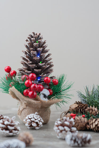 冬天用冬青浆果和树枝装饰的松果放在大理石桌上松树圣诞节圆锥体