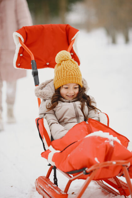 公园雪地公园里坐着雪橇的小女孩温暖毛衣户外