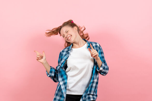 年轻女性正面图穿着格子衬衫的年轻女性在粉色背景上摆姿势跳舞年轻模特情感女童女人孩子女孩