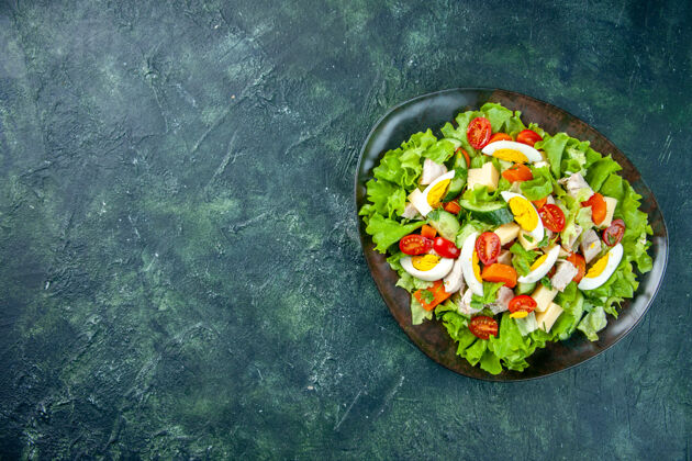 健康上图：绿色-黑色混合色桌子左侧的黑色盘子里的自制美味沙拉 有自由空间膳食蔬菜午餐