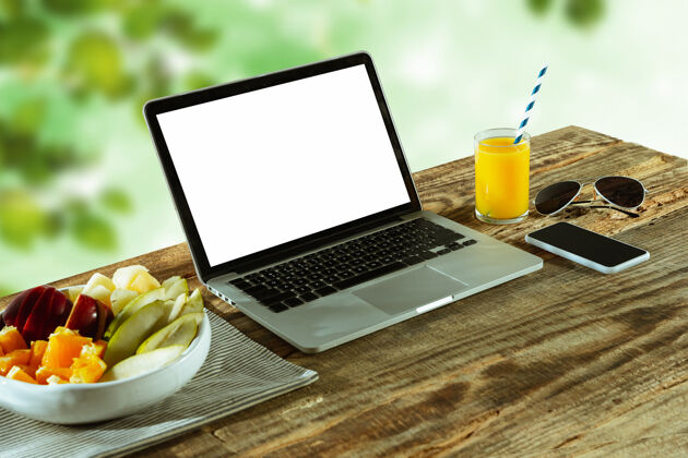 日记笔记本电脑和智能手机的空白屏幕放在户外的木桌上 与大自然同在键盘杯子桌面