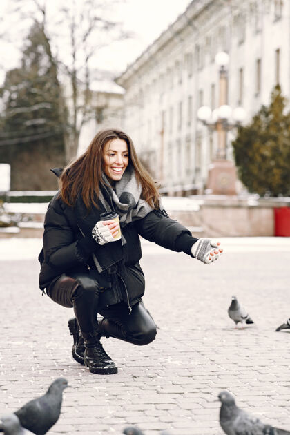 咖啡站在街上被鸽子包围的女人漂亮围巾寒冷