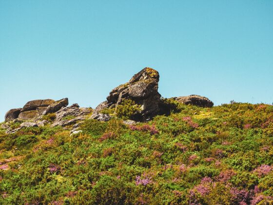 风景在多云的天空下 绿色的小山和巨大的岩石自然岩石云景