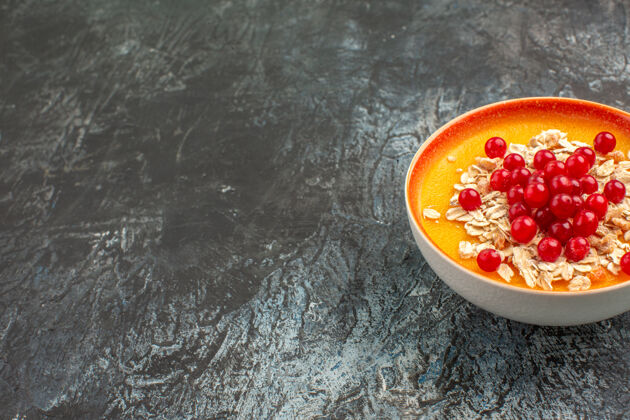 容器侧面特写镜头：灰色桌子上橙色碗里的开胃红醋栗特写碗可食用水果