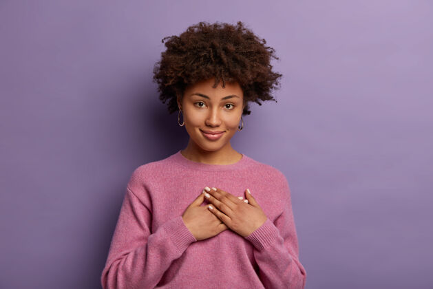 头发甜美的谢谢迷人的 感动的 真诚的美国黑人女人欣赏惊喜或可爱的礼物 手心紧握 非常感谢你 对着紫色的墙壁摆姿势非洲请套头衫