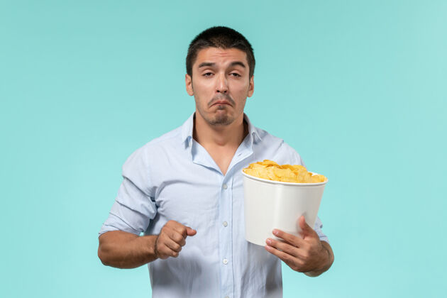 电影院正面图：年轻人拿着篮子 手里拿着土豆 一边看电影 一边在浅蓝色的墙上哭泣 一边看电影电影杯子肖像