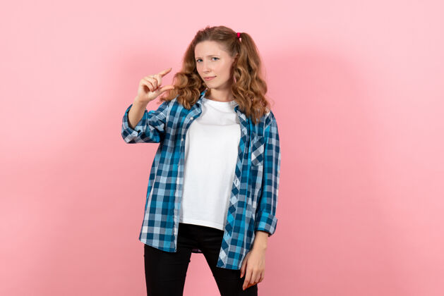衬衫正面图身着蓝色格子衬衫的年轻女性在粉色背景上摆姿势青春情感女孩模特儿时尚年轻漂亮格子