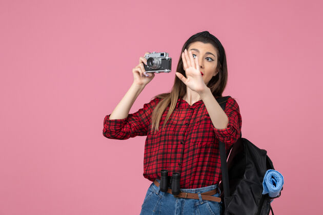 年轻女性正面图年轻女性用相机在粉色办公桌上拍照女性照片颜色表演桌子拍摄