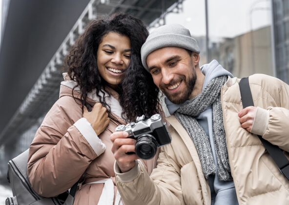 冬季中镜头的女人和男人带着相机季节户外旅行者