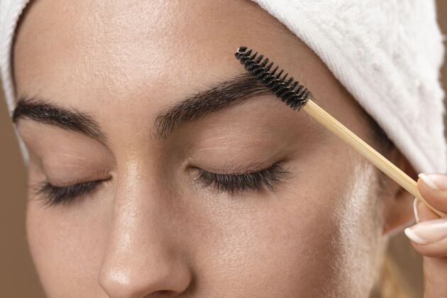 治疗年轻的女人在照顾她的眉毛自我护理美容眉毛