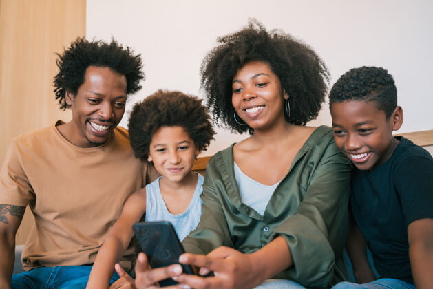 室内美国黑人家庭在家里用手机自拍的照片家庭和生活方式的概念父亲父母自拍