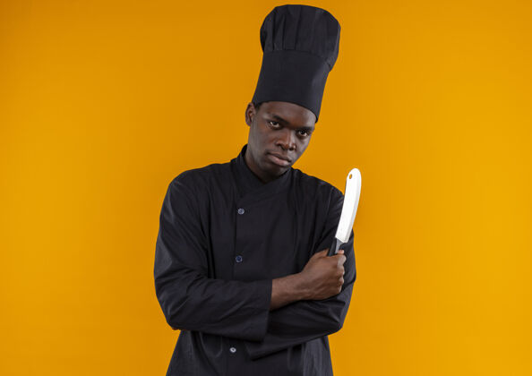 持有身着厨师制服的年轻自信的美国黑人厨师交叉双臂 持刀放在橘子上 留有复印空间年轻信心非裔美国人