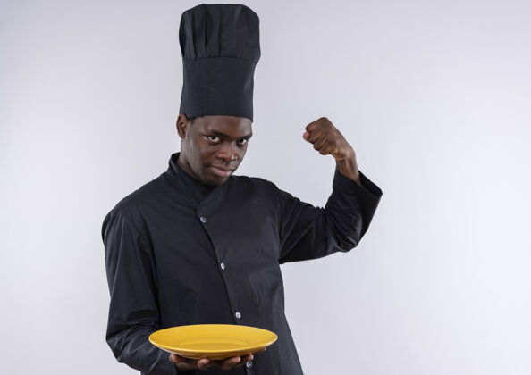 年轻年轻自信的美国黑人厨师穿着厨师制服 拿着盘子 在白色上绷紧二头肌 留有复印空间自信紧张二头肌