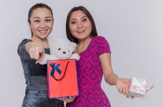国际两个快乐的亚洲女人拿着纸袋和泰迪熊熊目录庆祝