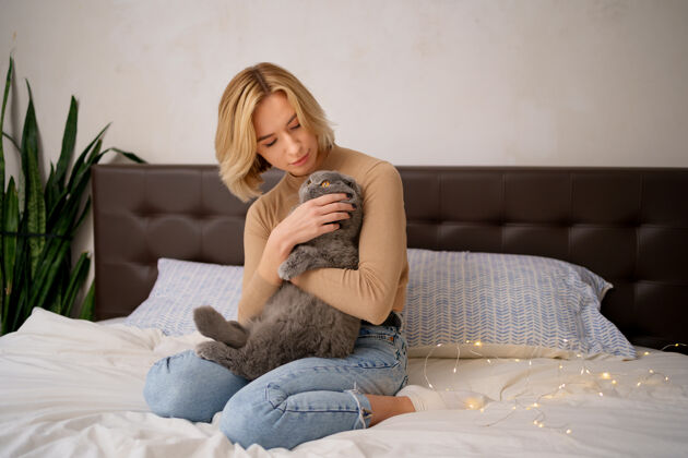 女性宠物 早晨 舒适 休息和人的概念-快乐的年轻女子与猫在床上在家猫主人蓬松