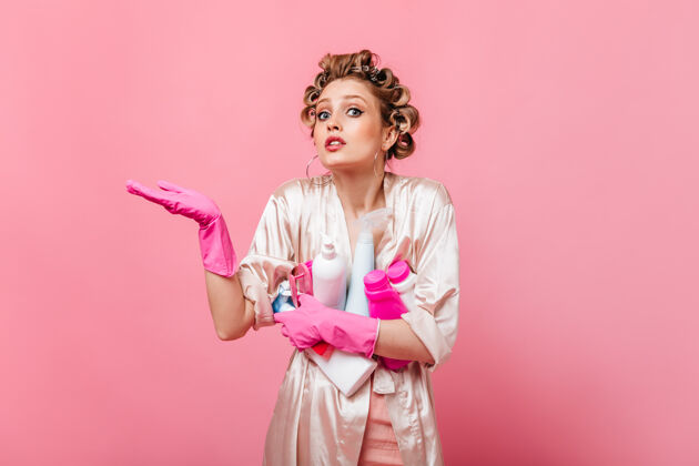 脸金发女人看着前面 把洗衣粉放在粉红色的墙上女性成人手套