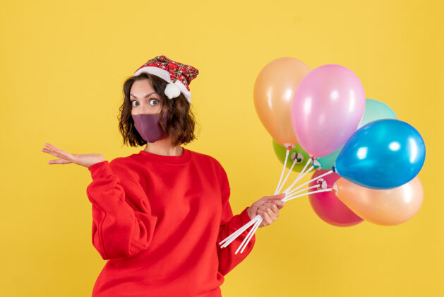 年轻女人正面图：一个拿着气球的年轻女子站在黄色的椅子上庆祝气球女人