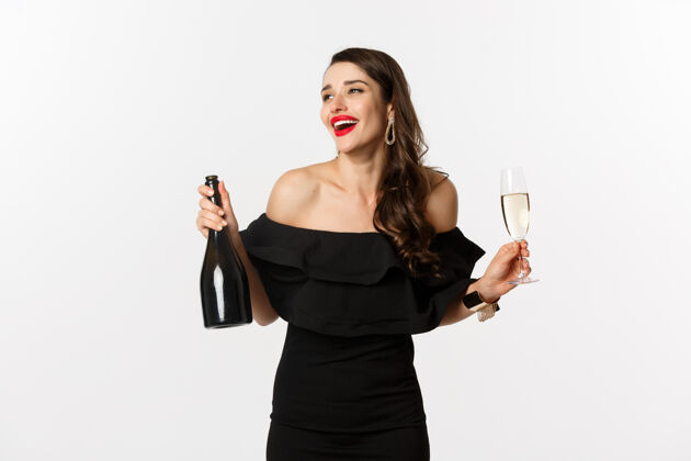 美丽庆祝和派对的概念时尚的黑发女人穿着迷人的裙子 拿着一瓶香槟和一杯香槟 在新年假期里玩得很开心黑发口红庆祝