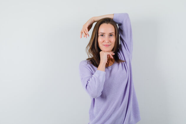 衬衫年轻的女性抬起手臂在头上 同时在她的淡紫色衬衫 看着令人印象深刻的手靠着自信卷发优雅