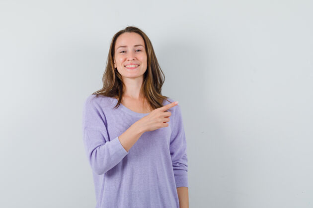 欢快年轻的女性指着旁边的淡紫色衬衫 看起来很高兴衬衫女性漂亮