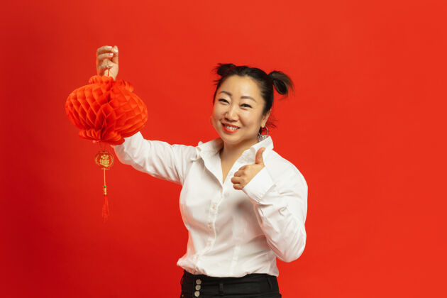 中文意境装饰亚洲年轻女子手持传统服饰的红墙上的灯笼微笑 竖起大拇指庆祝 人类的情感 节日复制空间美丽普通话庆典