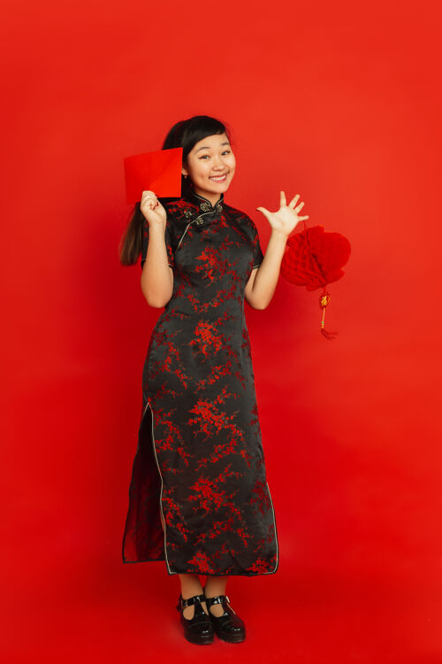 节日年轻的亚洲女人拿着红包和中国灯笼隔离在红墙上手青少年服饰