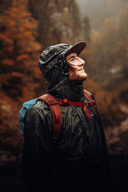 人穿红黑夹克戴黑帽子的男人站在雨中奥地利徒步旅行