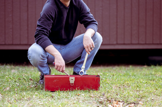 工具箱一个穿着牛仔裤的男人拿着一把扳手和一个红色的工具箱伙计裤子扳手