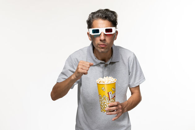 年轻男性正面图年轻男性戴着d型太阳镜在白色表面吃爆米花衬衫电影院男性