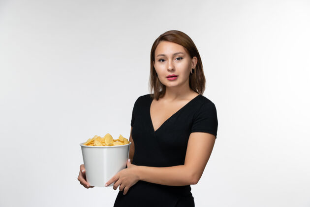 孤独正面图身穿黑色衬衫的年轻女性手持薯片 在白色表面摆姿势漂亮电影院秘书