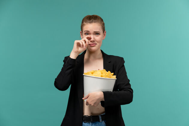 年轻的女性正面图年轻女性拿着吃薯片看电影 在蓝色的水面上哭泣西装商务女电影院