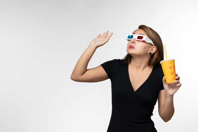 苏打水正面图戴着d型太阳镜拿着苏打水的年轻女性仰望白色表面面部电影院年轻的女性