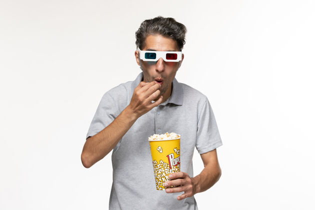 商务人士正面图：戴着d型太阳镜在白色表面上吃爆米花的年轻男性太阳镜偏远青少年
