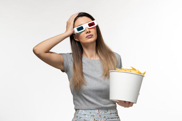 女的正面图年轻女性手持芯片 戴着d型太阳镜在浅白色表面看电影前面的电影院太阳镜