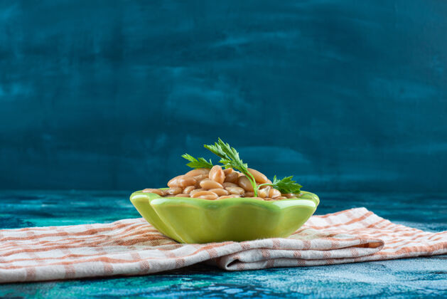 茶毛巾一碗烤豆放在茶巾上 蓝色背景可口美味风味
