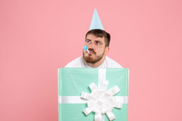 颜色正面图：年轻男性站在礼物盒内 穿着粉色睡衣 参加派对 享受圣诞快乐睡眠成人男性