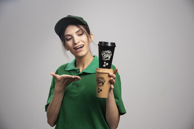 女孩穿着绿色制服拿着咖啡杯的女送货员女性员工承运人
