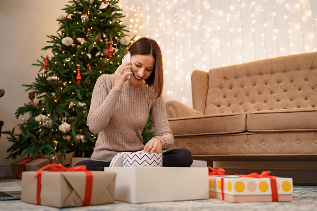 互联网一个女人在圣诞节坐着 一边包装圣诞礼物一边打电话圣诞节女人房子